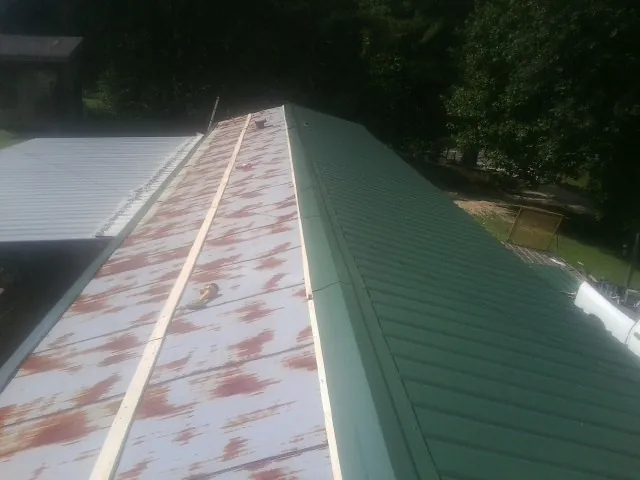 Old rusted panels beside newly installed green metal roofing — Wind Damage Roof Repair by Roofing Brothers in Weber City