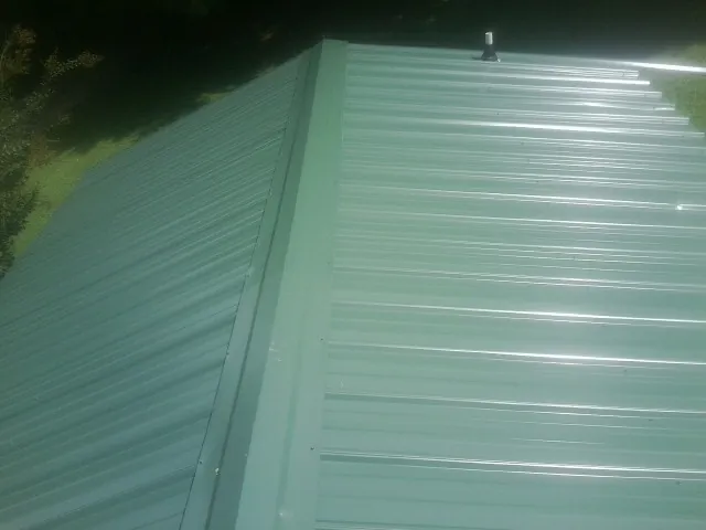 New green metal panels meeting at the ridge of a roof — Flat Roof Repair work by our crew in Weber City