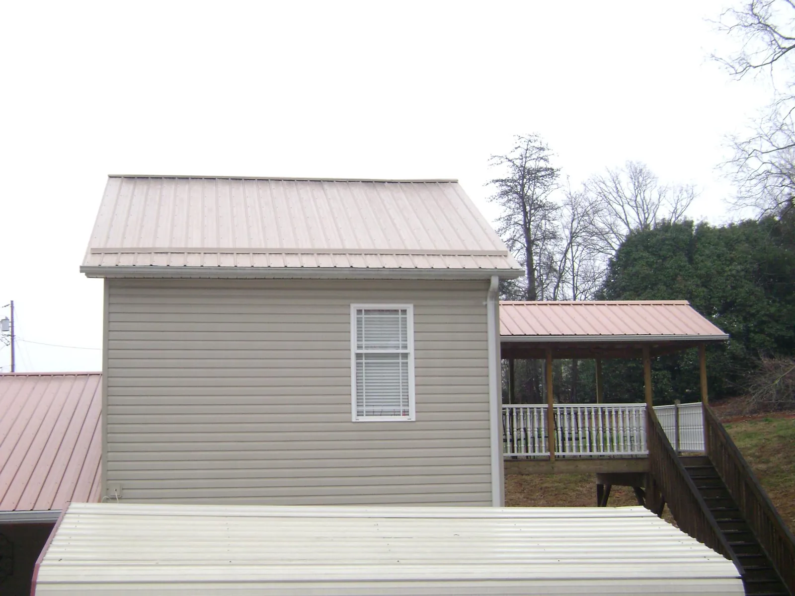 Tan metal roofs on a two story addition and attached porch, from a Roof Replacement job in Weber City