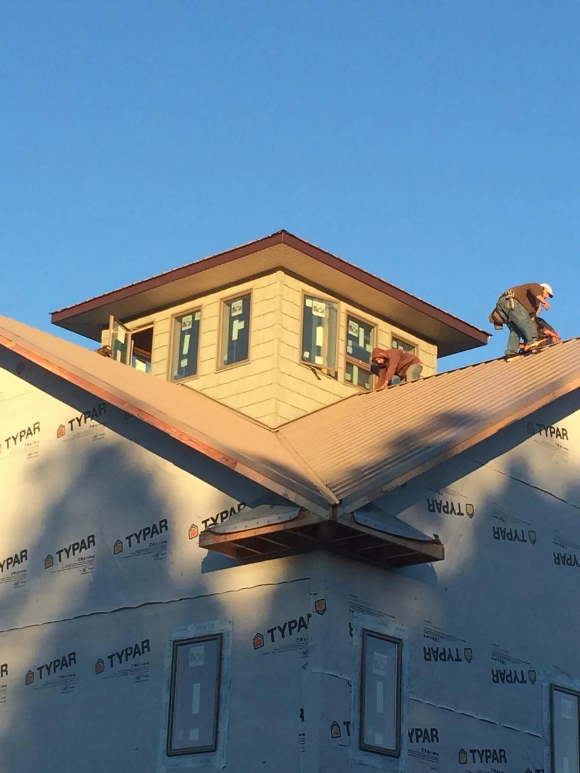 Roofers working around a rooftop cupola on a new metal roof at sunset — Roof Waterproofing in Weber City by Roofing Brothers